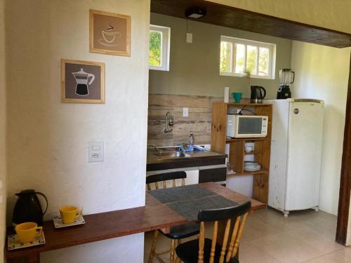 uma pequena cozinha com uma mesa e um frigorífico em SURF PARADISE apartamentos em Pinheira