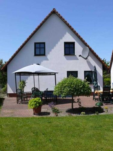 a large white house with benches and an umbrella at Ruegen_Fewo 33_1 in Gingst