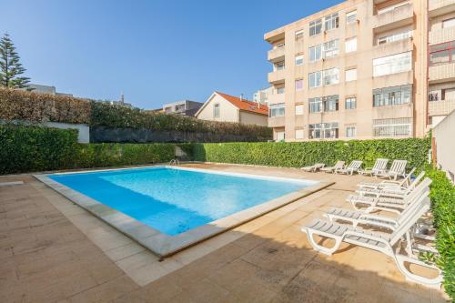 a swimming pool with lounge chairs and a building at Penthouse Praia de Olinda - Minho's Guest in Vila do Conde
