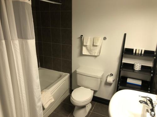 a bathroom with a white toilet and a tub and a sink at Monastery Hotel in St. John's