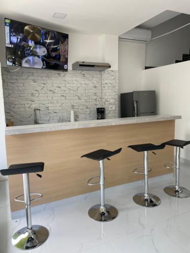 a kitchen with three bar stools in front of a counter at Hotel Sabana Inn in San José