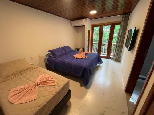 a bedroom with two beds with purple sheets and a window at Pousada Pedras Quentes in Lençóis
