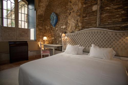 a bedroom with a large white bed with a brick wall at Apartamentos Sharis in Jerez de la Frontera