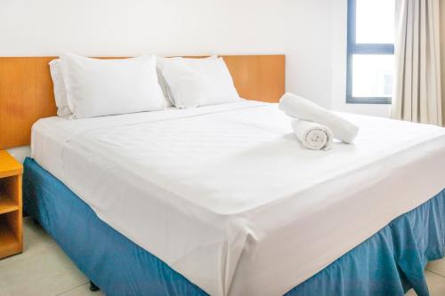 Una gran cama blanca con reloj. en Praia a Vista Salvador Hotel en Salvador
