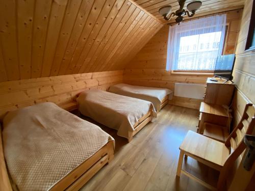 a bedroom with two beds in a wooden room at Nowica 71 Relax Dom Świerkowy in Nowica