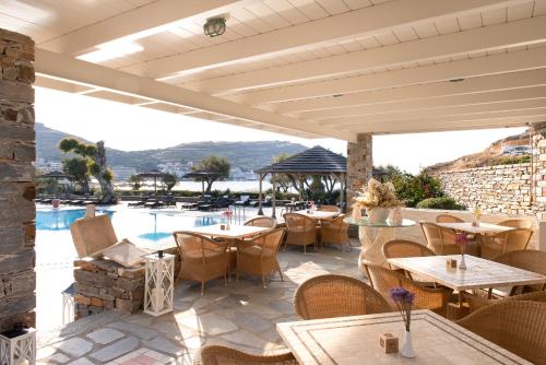 a patio with tables and chairs and a swimming pool at Porto Kea Suites in Korissia