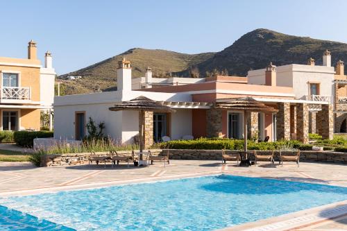 a villa with a swimming pool in front of a house at Porto Kea Suites in Korissia