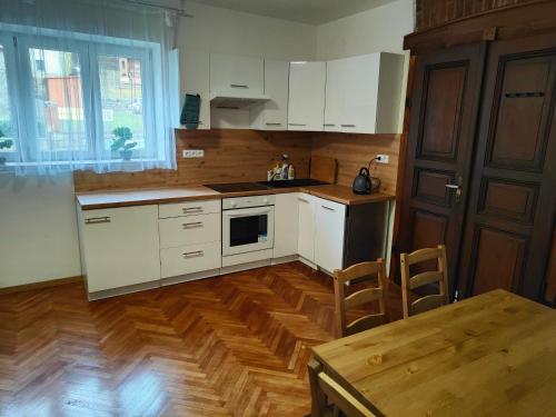 a kitchen with white cabinets and a wooden floor at Apartmány Na Cestě in Desná