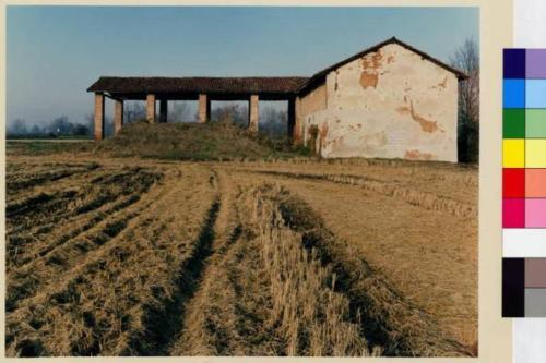 an old barn in a field with a dirt road at Agriturismo Le Risaie in Basiglio