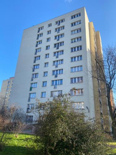 un edificio alto y blanco con árboles delante en Brand New Top Floor Apartment at Mokotow, en Varsovia