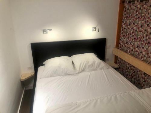 ein Bett mit einem schwarzen Kopfteil in einem Schlafzimmer in der Unterkunft Appartement Les Arcs 1800 - Charmettoger in Bourg-Saint-Maurice
