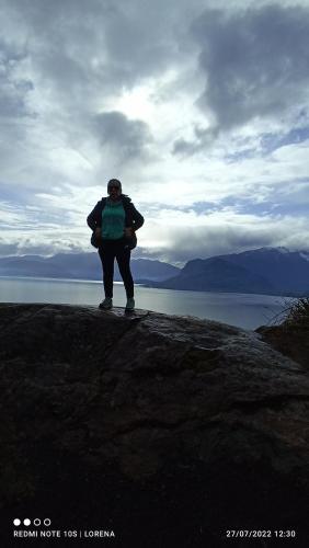 a man standing on a rock near the water at Casa de campo Llifén Futrono Lago Ranco in Ranco