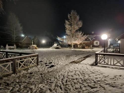 a snow covered yard at night with a fence at Podlaski Zakątek in Bereżyszcze