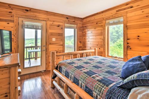 a log cabin bedroom with a bed and windows at Fleetwood Cabin with Hot Tub Near Blue Ridge Pkwy! in Fleetwood