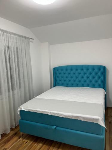 a bed with a blue headboard in a bedroom at Cezar Apartments in Podgorica