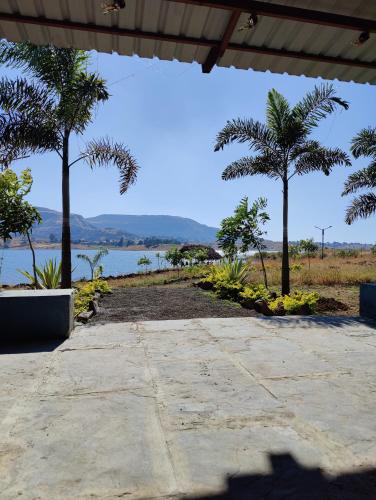 a patio with palm trees and a body of water at Mountain N Lake Resort in Igatpuri