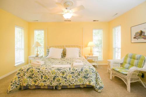 a bedroom with a bed and a chair and windows at South Beach Lane 47 in Hilton Head Island