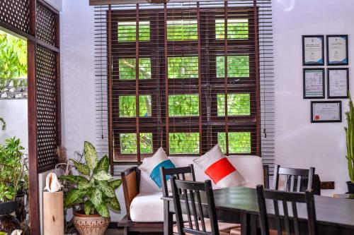 uma sala de estar com uma mesa, cadeiras e janelas em Suvaasa Inn em Omadhoo