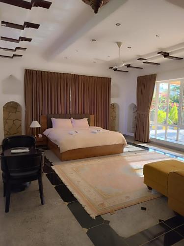 um quarto com uma cama grande e uma cadeira em Valley CLIFF INN em Al Jināh