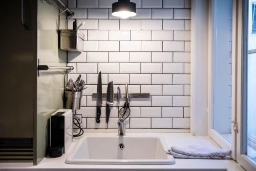 un fregadero en una cocina con una pared de azulejos blancos en Kings Square 2BR by Daniel&Jacob's, en Copenhague