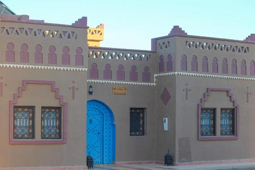 a large building with a blue door and a building at Riad Hassi Labied Merzouga in Merzouga