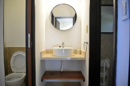 y baño con lavabo, espejo y aseo. en La Salamandra. Casa en la Sierra en Tandil