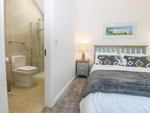 a bedroom with a bed and a shower and a toilet at Yr Hen Feudy in Moelfre