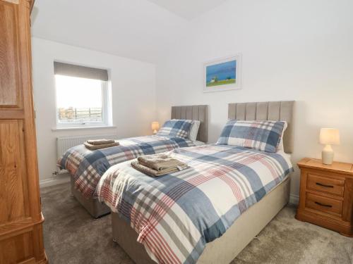 a bedroom with two beds and a window at Yr Hen Feudy in Moelfre