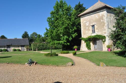 an old stone house with a gravel driveway at La tour du Grand Boust in Longué