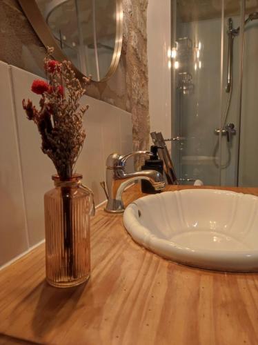 La salle de bains est pourvue d'un lavabo et d'un vase avec des fleurs. dans l'établissement La tour du Grand Boust, à Longué