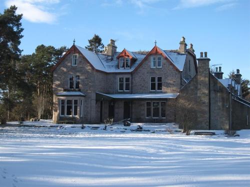 uma grande casa de tijolos com neve no chão em Dalrachney Lodge em Carrbridge