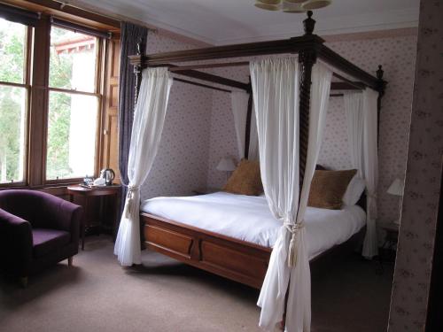 Schlafzimmer mit Himmelbett und weißen Vorhängen in der Unterkunft Dalrachney Lodge in Carrbridge