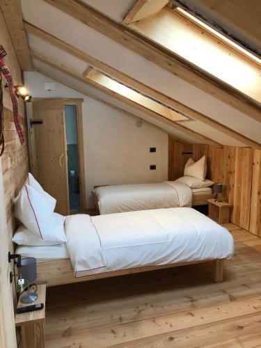 two beds in a room with wooden floors at Lärchenwirt Dolomites in San Nicolò di Comelico