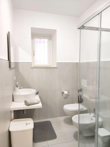 a white bathroom with a toilet and a sink at Central rooms in Agira