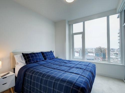 a bedroom with a blue bed and a large window at Admiral's Anchor by IRIS PROPERTIES! in Victoria