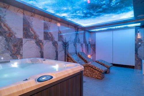 a room with a jacuzzi tub in a room with chairs at Protekal Wellness & SPA in Zlatibor
