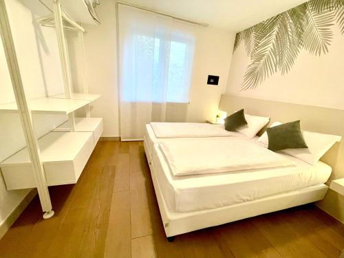 a white bedroom with two beds and a window at Residence Verdeblu in Arco