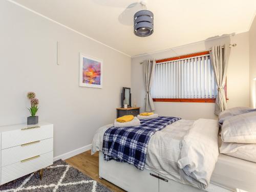 um quarto com uma cama, uma cómoda e uma janela em Parkhill Cottage em Kildary