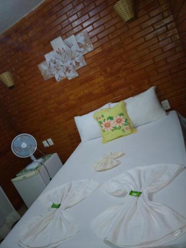 a bedroom with a white bed with a brick wall at Pousada Central in Santana do Riacho