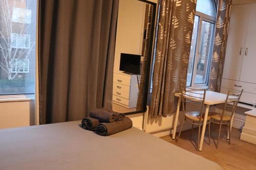 a bedroom with a bed and a table with a chair at Studio on Finchley Road in London