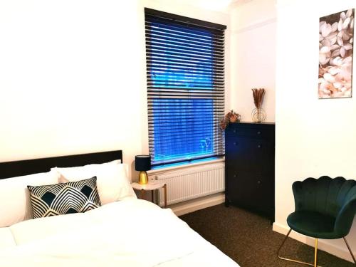 a bedroom with a bed and a chair and a window at Lovely 1 Bed Flat in Trendy Peckham in London