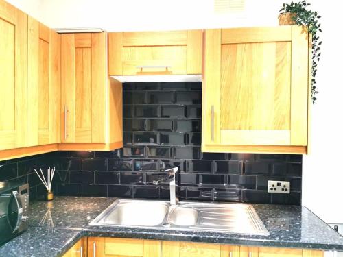 a kitchen with a sink and a black tile wall at Lovely 1 Bed Flat in Trendy Peckham in London