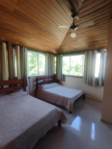 two beds in a room with two windows at Apart da Cachoeira in Florianópolis