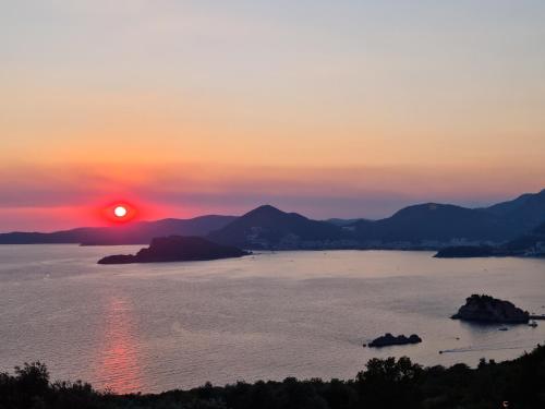a sunset over a body of water with mountains at Villa Frida in Sveti Stefan