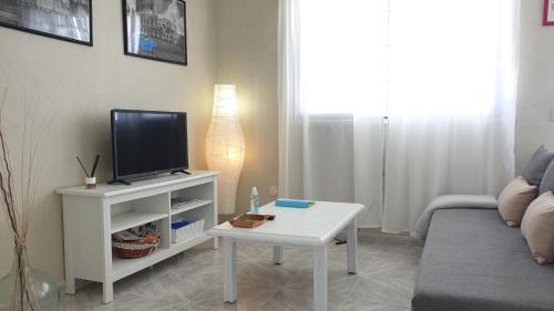 ein Wohnzimmer mit einem TV und einem weißen Tisch in der Unterkunft Vistas para el relax in Puntallana