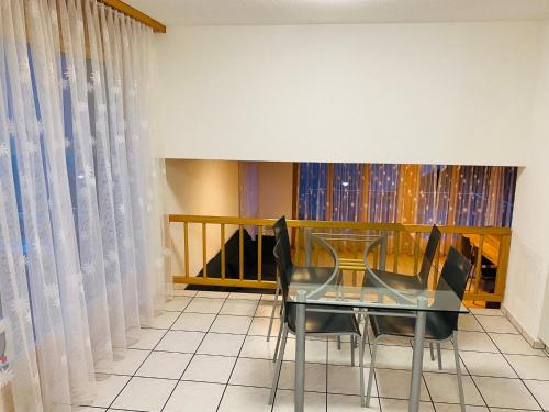 a dining room with a glass table and chairs at Lake View Residence in Niederried