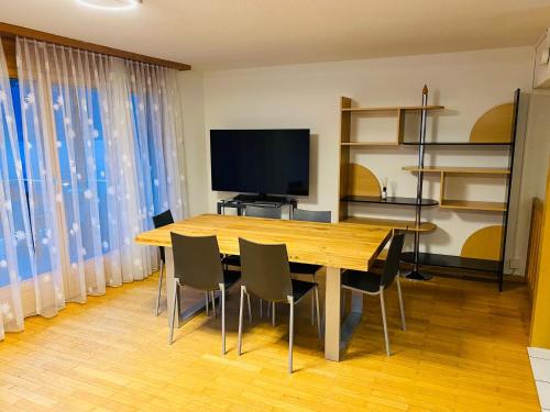 a dining room with a table and chairs and a television at Lake View Residence in Niederried