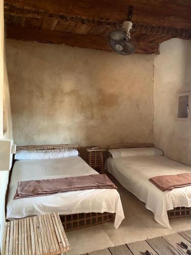 a room with two beds and a ceiling at Siwa Desert Home in ‘Izbat Ţanāţī