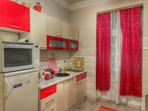 a kitchen with a microwave and a red curtain at A Towns Charm in Sarajevo