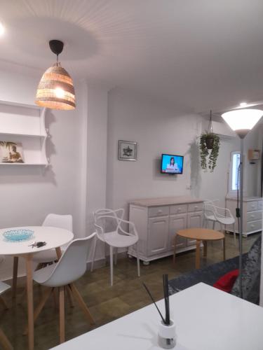 カディスにあるEstudio Carmenの白いテーブルと椅子、テレビが備わる客室です。